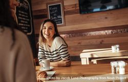 Smiling woman sitting in a restaurant talking to her friend 4Me6k4