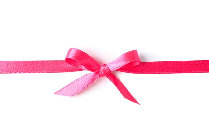 Pink ribbon with bow isolated on plain background. Gift concept