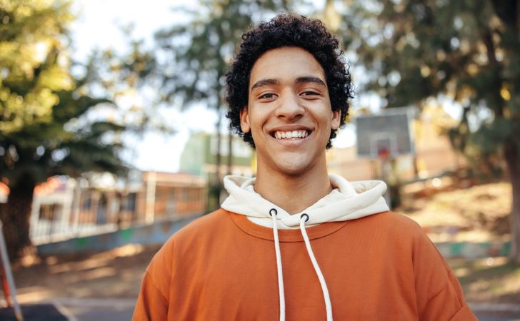 Portrait of smiling male teenager wearing casual clothes in city park