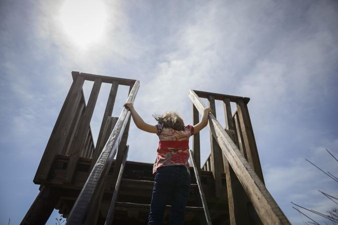 Child climbing up to observation tower on sunny day