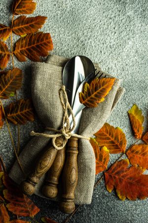 Fall table setting with orange yellow leaves on stone background