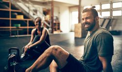 Two happy people sitting on gym floor