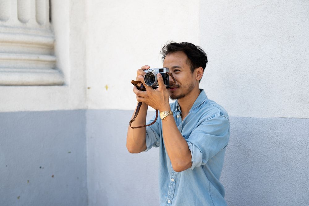 Man photographer taking photos with digital camera and looking serious