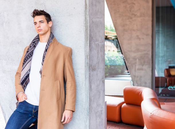 Front view of man wearing winter clothes leaning on wall outside