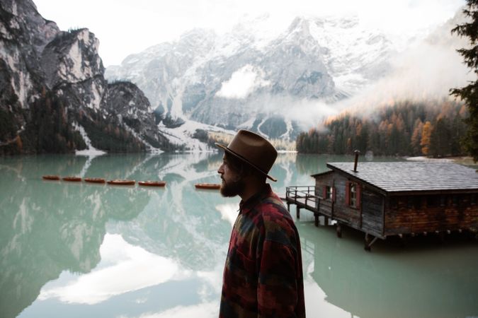 Resting man in casual wear delighting in views near lake and mountains