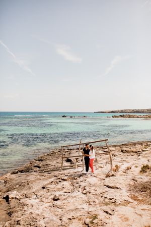 Amorous couple hugging on coastal pier