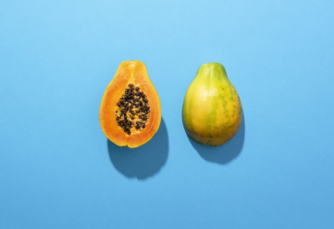Ripe papaya fruit cut in half on blue table