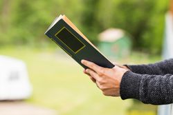 Cropped anonymous man reading book on terrace of house