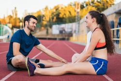 Two athletes stretching after an athletics training session.
