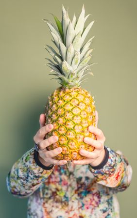 Woman holding pineapple in front of face
