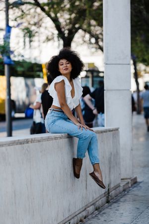 Black female siting on railing outdoors