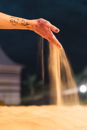 Crop hand spilling dry sand