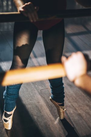 Crop shot of professional dancer in pointe shoes standing on tiptoes in studio.