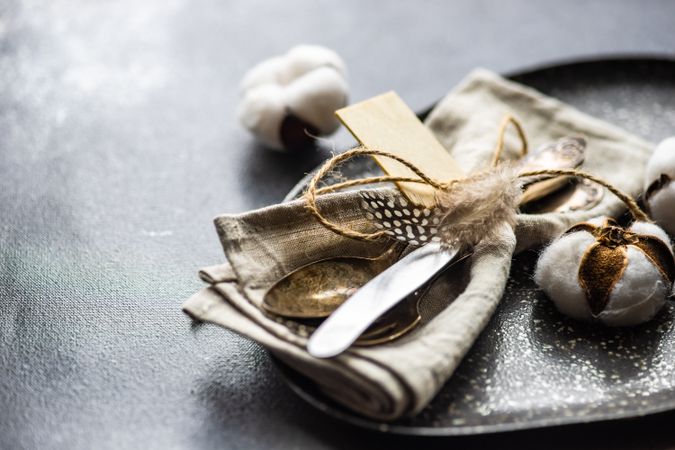 Table setting on concrete background with decorative cotton and feathers with napkin on plate