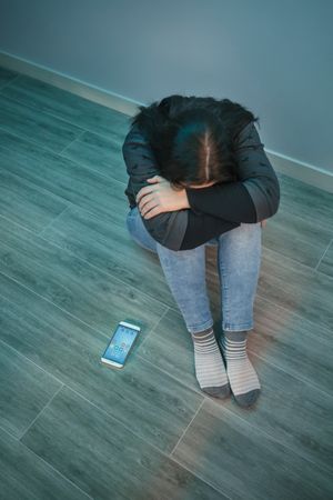 Unrecognizable desperate woman with phone addiction covering her face