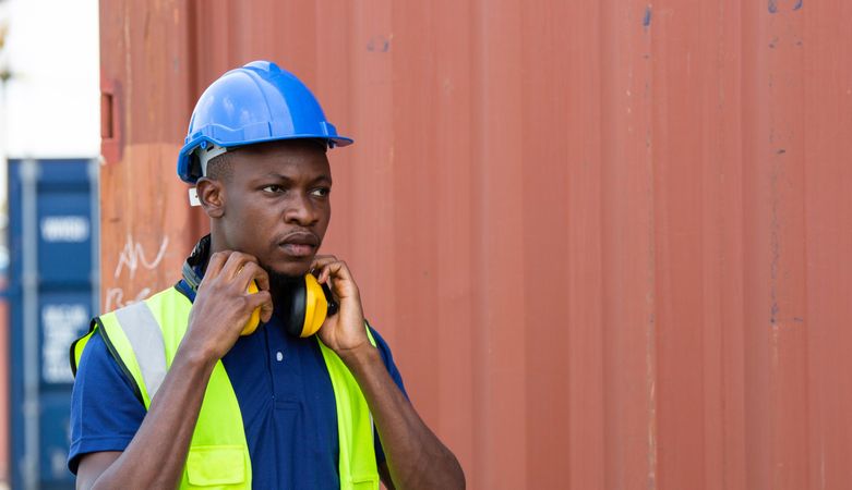 Black construction site worker in high vis jacket, ear protection and hard hard