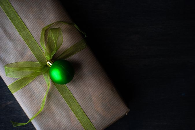 Top view of gift with green ribbon and Christmas bauble