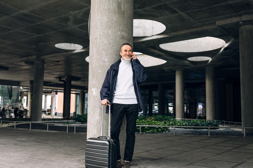 Stylish mature tourist standing outdoors smiling with phone