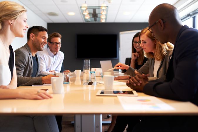 Business associates sitting in board room having a meeting with coffee and tablets