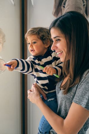 Adorable toddler with mom near window
