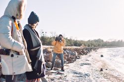 Friends taking photos on the coast on a cold day