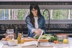 woman reading recipe while preparing food in the kitchen.