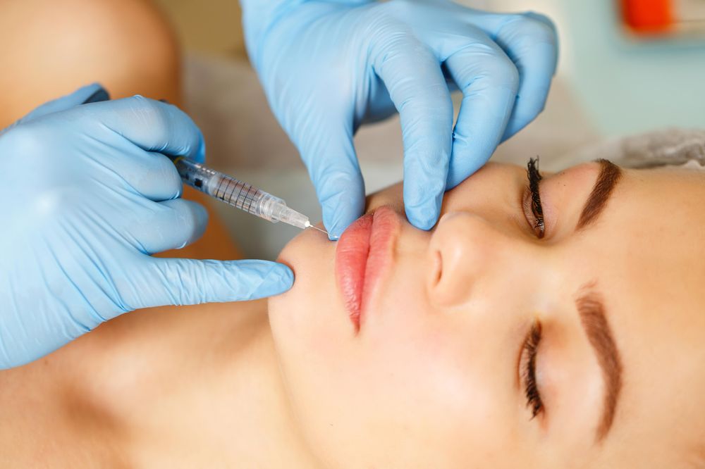 Hands in latex gloves providing injectable beauty treatment for client