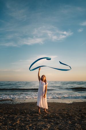 Adorable girl playing with ribbon on seaside