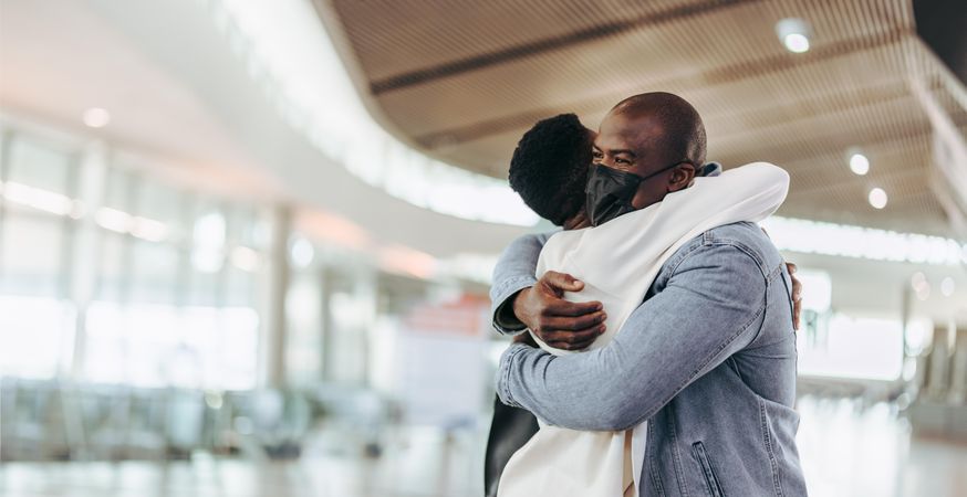 Male traveler giving big hug to his wife at airport
