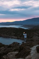 Solo man overlooking coast as the sun goes down