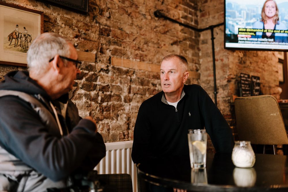 Two mature men talking over drinks at a pub