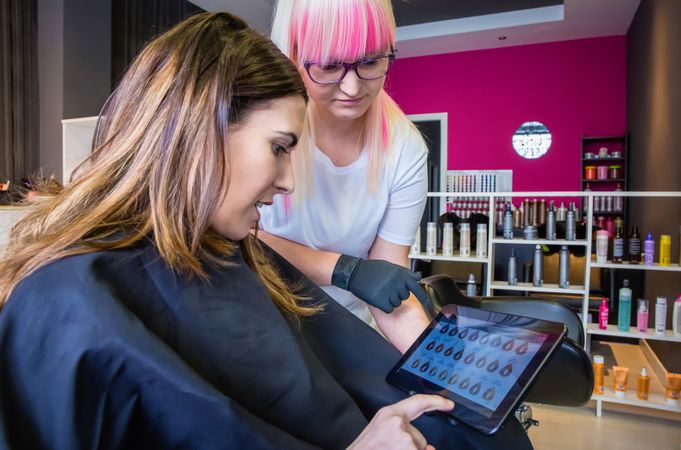 Hairdresser and client choosing hair color from digital tablet