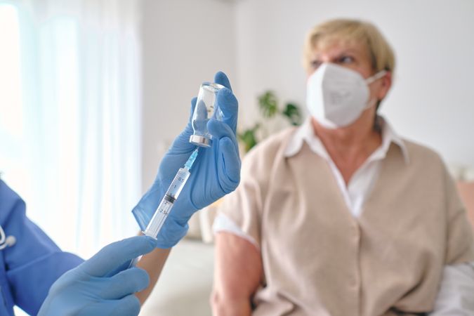 Crop doctor filling syringe with vaccine against patient at home