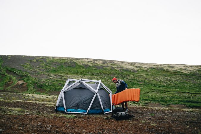 Man setting up tent in a green field