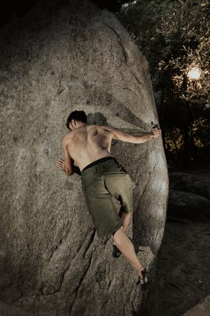 Man practicing rock climbing among large rocks in a forest