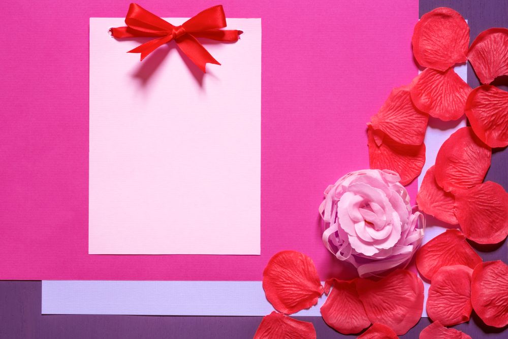 Blank paper note with bow and petals with copy space