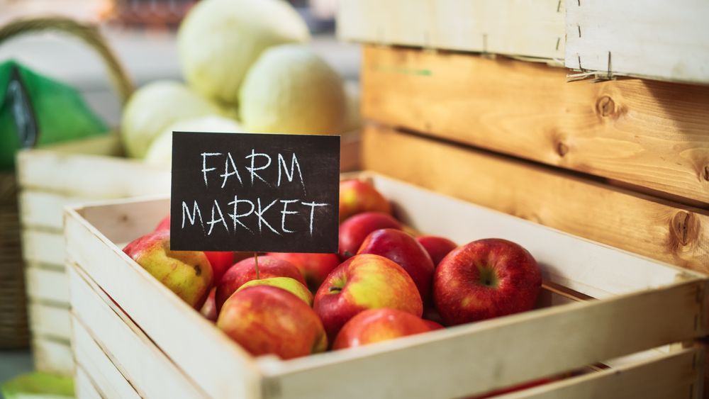 Selection of Tasty Red Apples with a Farm Market Sign on a Food Stall with Fresh Organic Fruits and Vegetables.