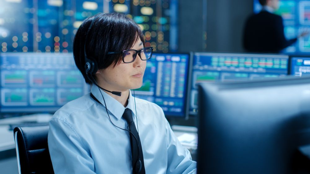 In the Network Operations Center Trader Makes Personal Client Call with a Headset.