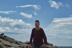 Middle aged man standing on rocky beach