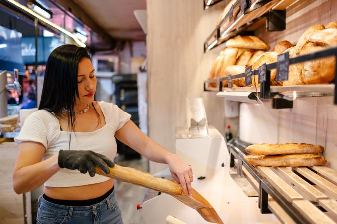 Young sales clerk putting bread in a bag
