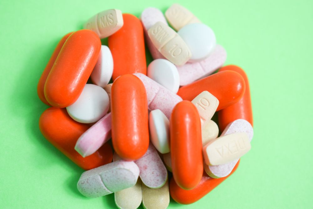 Variety of colorful medication and vitamins in center of green table