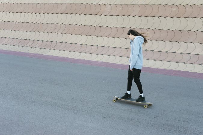 Teenage girl skating on a longboard on road