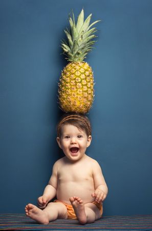 Happy baby holding a pineapple over her head
