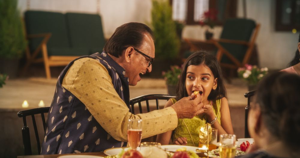 Family Time and Good Happy Memories: Indian Grandfather and Cute Granddaughter Sharing Food and Fruits
