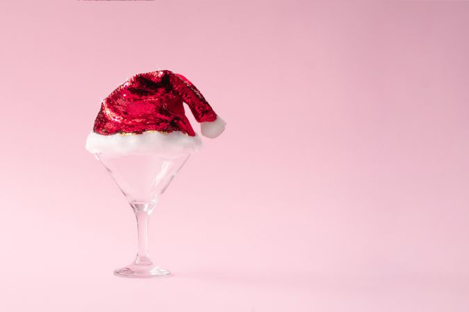 Martini glass with sequin Santa hat on pink background