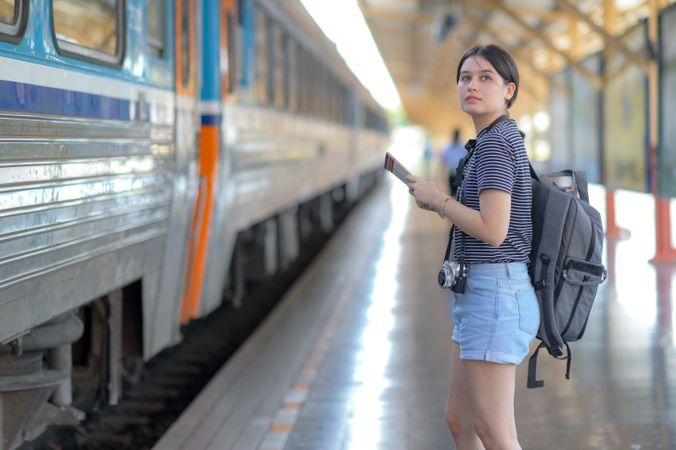 A female traveler with a rucksack waiting for a train