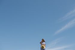 Traveling young female taking photo against blue sky