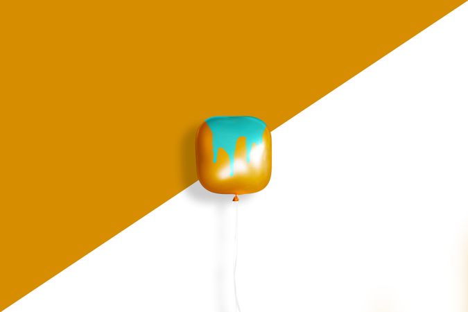 Square orange balloon with paint dripping on it on an orange background