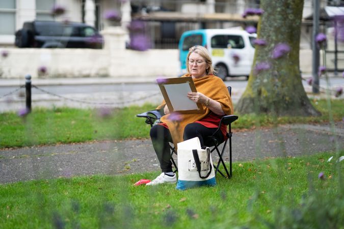 Older woman sitting calmly outside drawing