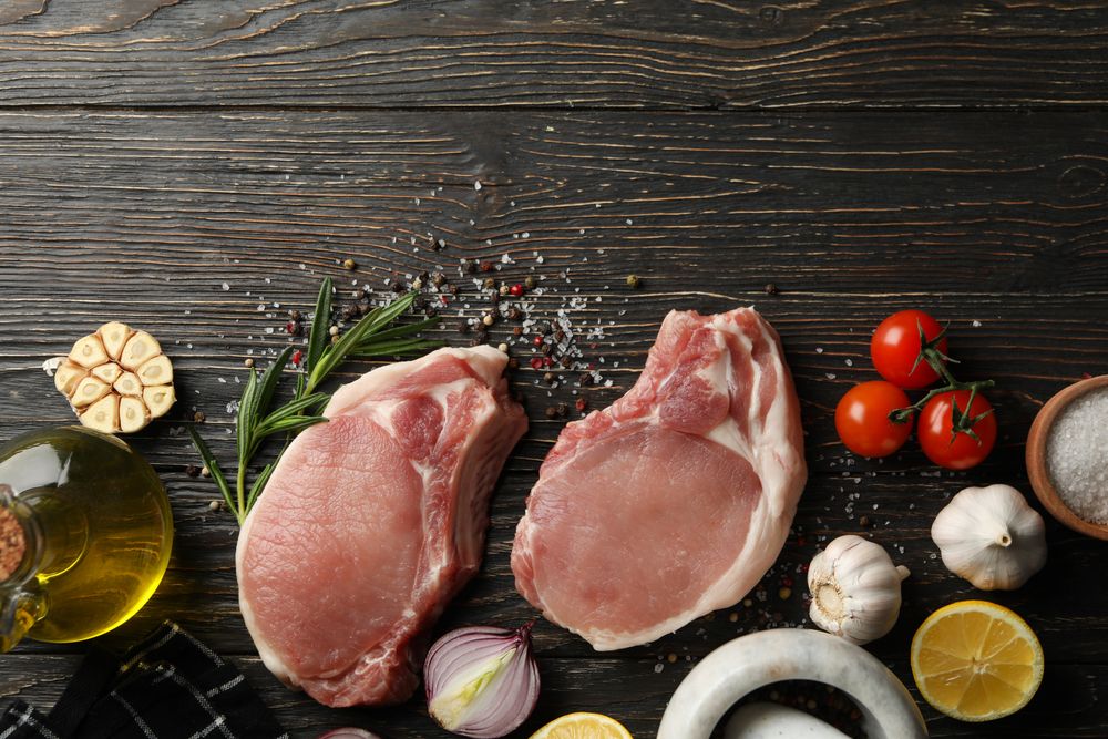Composition with raw meat for steak and ingredients on wooden background